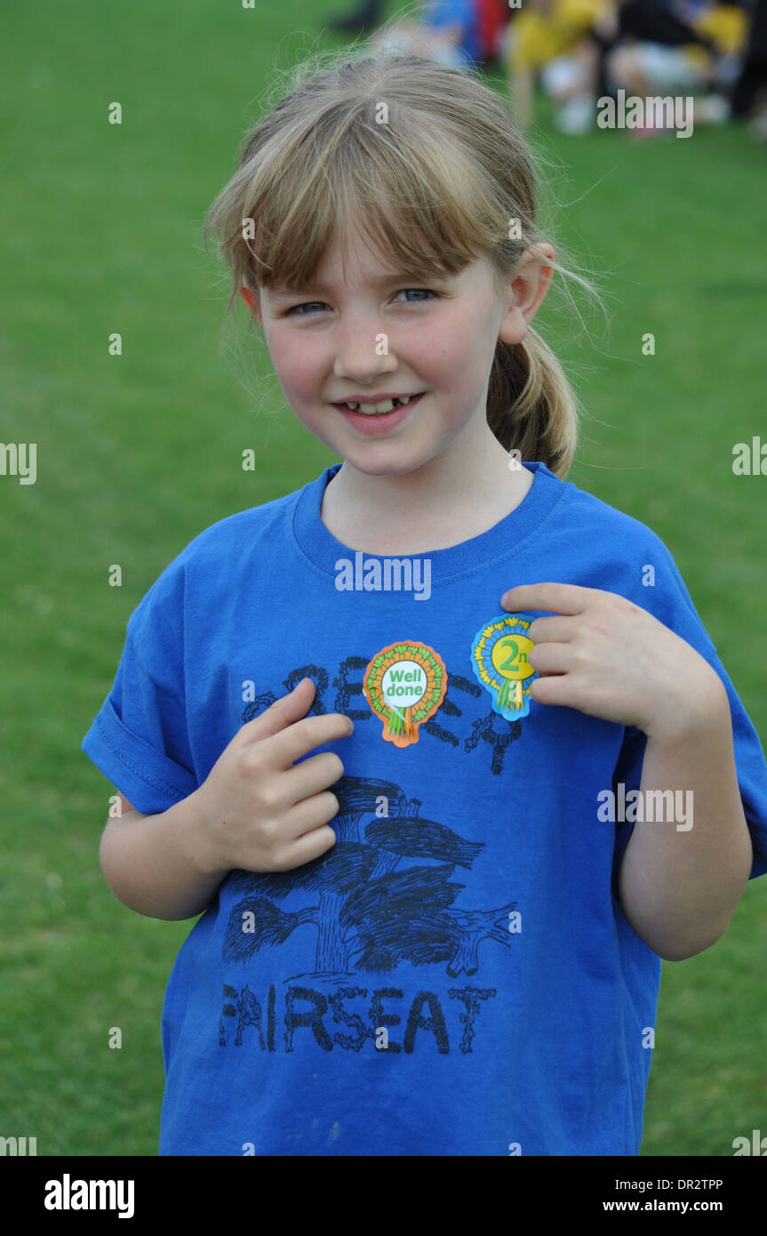 portrait of little blonde girl showing off her stickers at primary school sports day Stock Photo