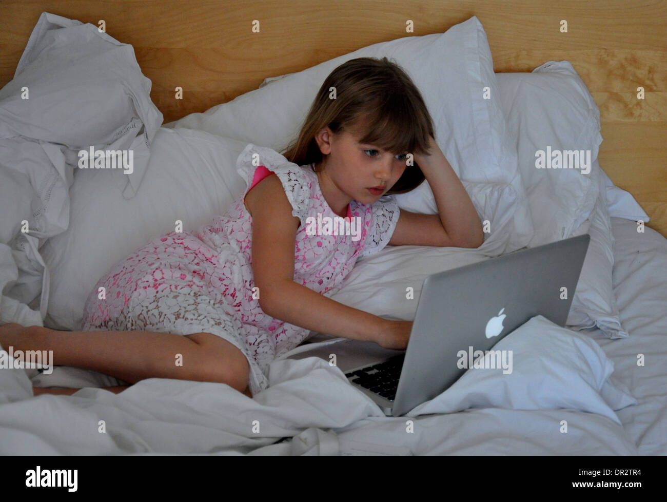 Portrait of a little girl looking shocked at a computer screen Stock Photo