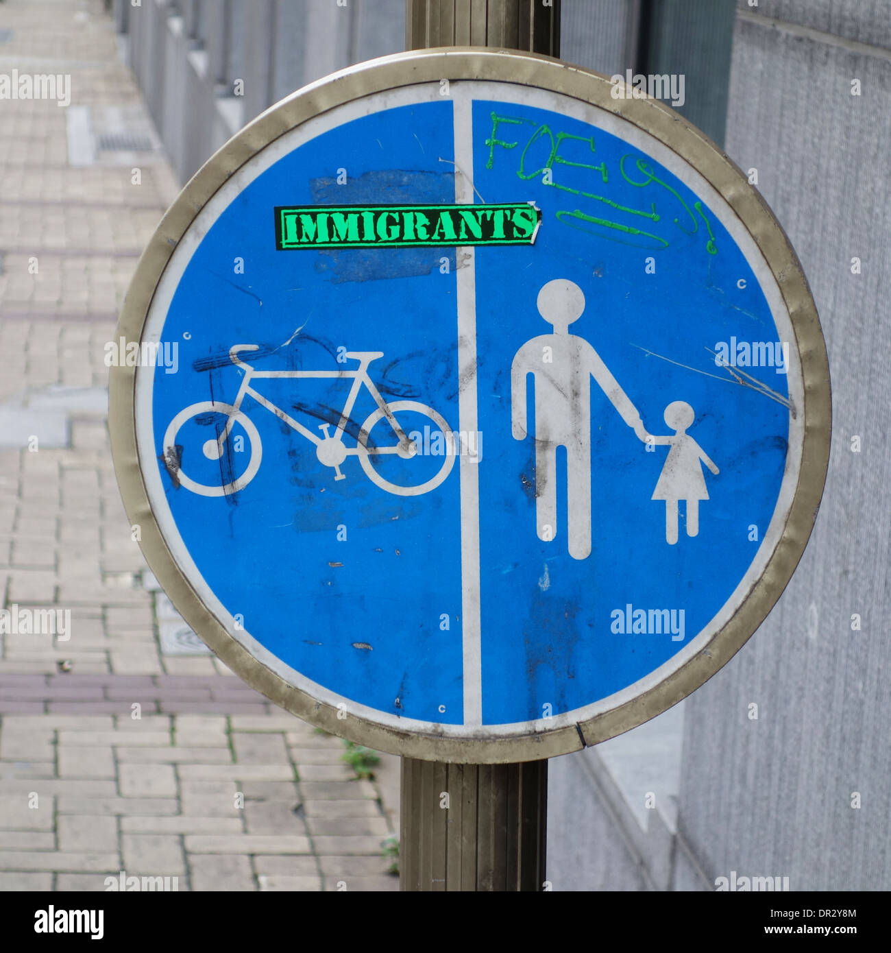 Brussels, Belgium - 23 December 2013: 'Immigrants' sticker on a traffic sign on a street in central Brussels, Belgium. Stock Photo