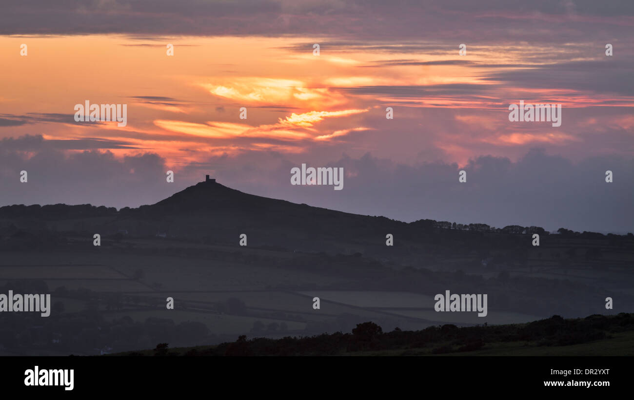 A shot of the sun setting behind Brentor, taken from the car park underneath Great Staple Tor. Stock Photo