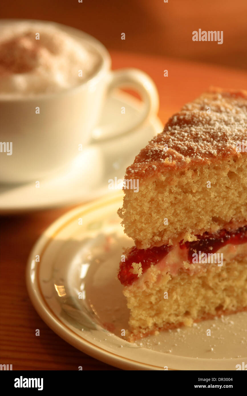 Cake and Coffee cappuccino with a slice of jam and cream filled sponge