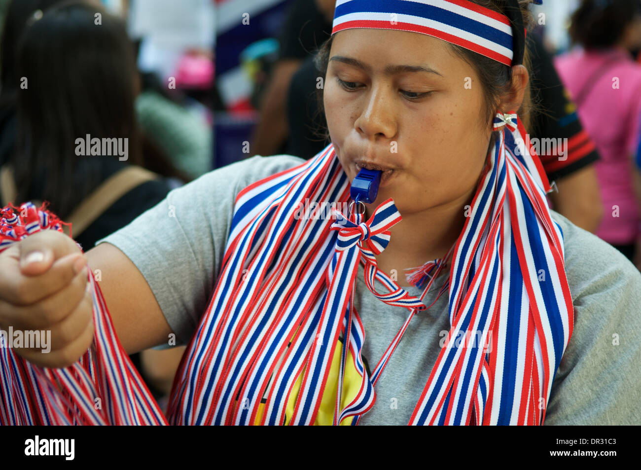 Bangkok, Thailand. Jan. 18th, 2014. Thai anti-government protester blowing her whistle. blowing whistles has become a trademark of the current protests. After a deadly bomb attack on Friday in Bangkok, Tens of thousands of protesters took to the streets to demand the resignation of Thai Prime Minister Yingluck Shinawatra. 'Shutdown Bangkok' is organized by the People's Democratic Reform Committee (PDRC). Credit:  Kraig Lieb / Alamy Live News Stock Photo