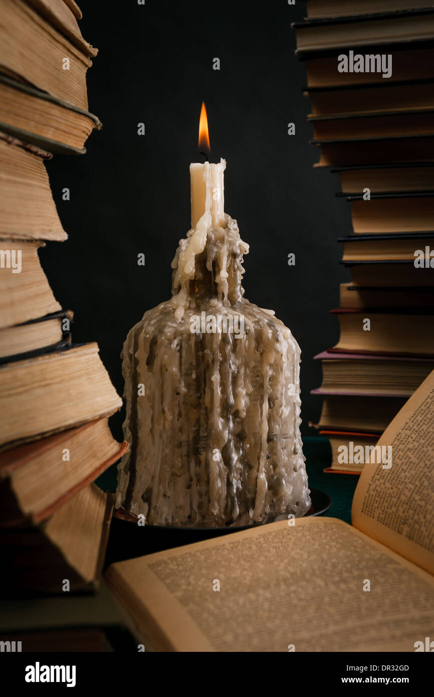 a melting candle in a bottle among old books Stock Photo