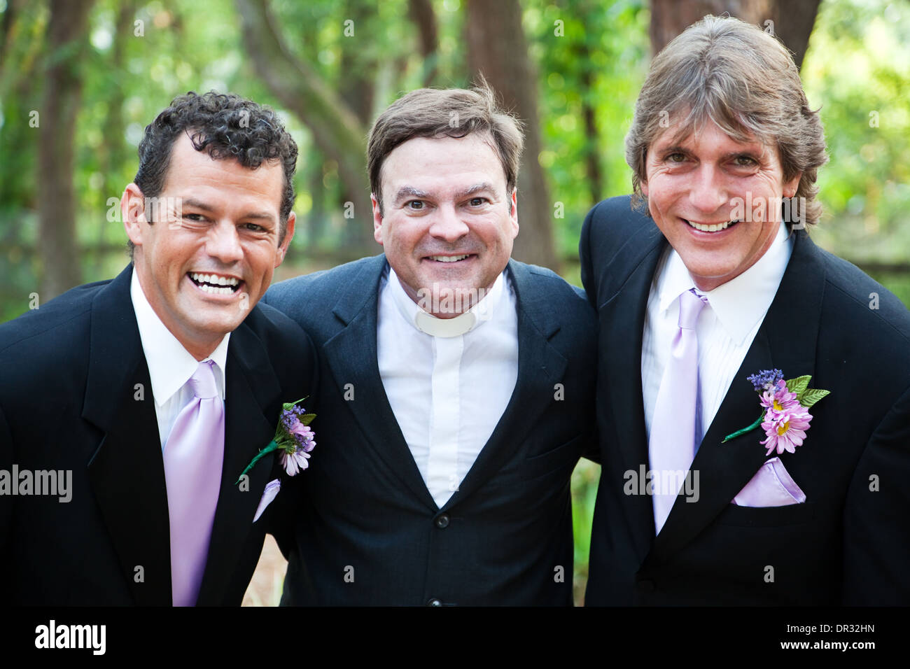 Minister posing with a handsome gay wedding couple he has just married. *focus is on the minister. Stock Photo