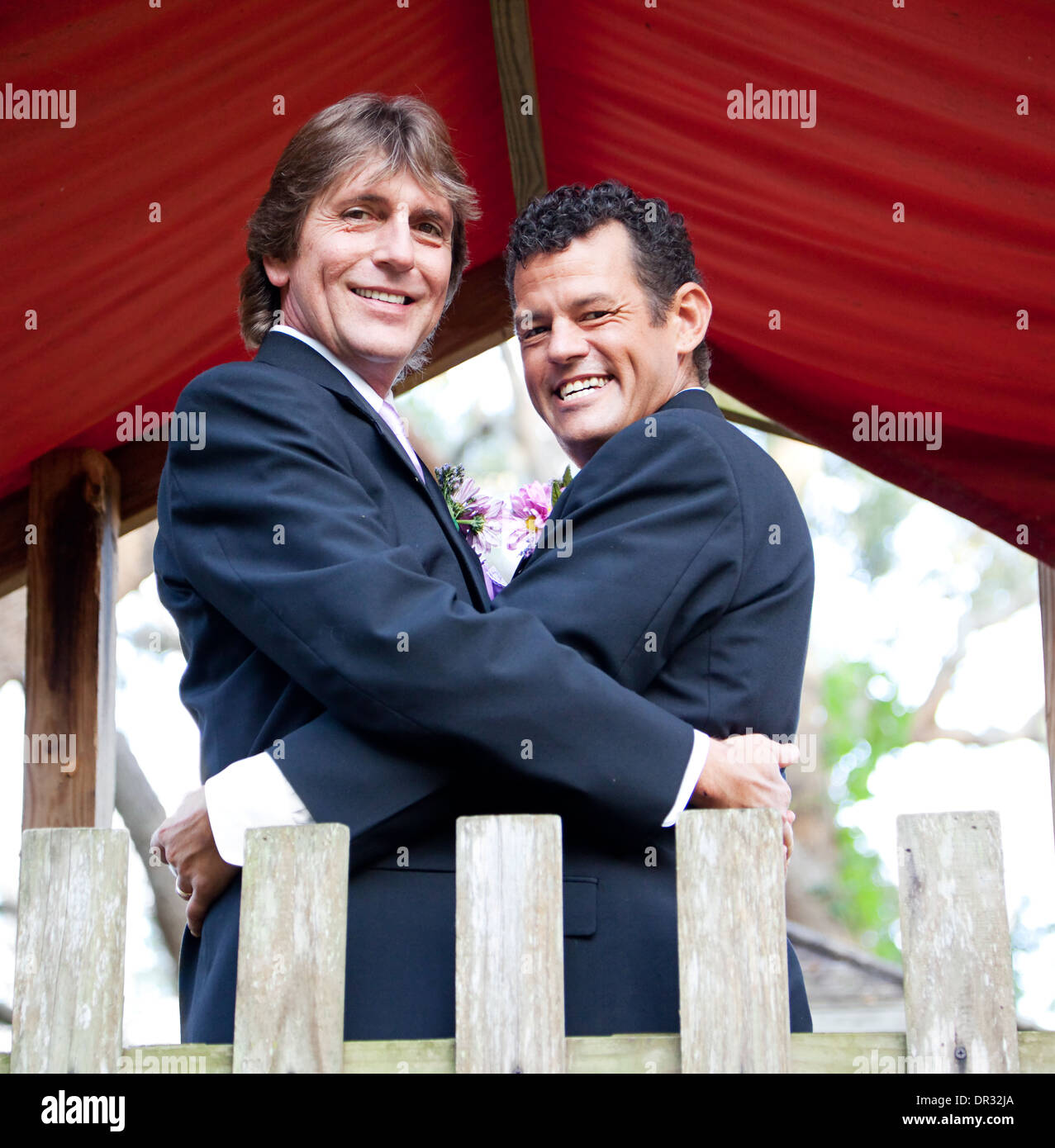 Portrait of a newly married gay couple embracing on a playground in the park.  Stock Photo