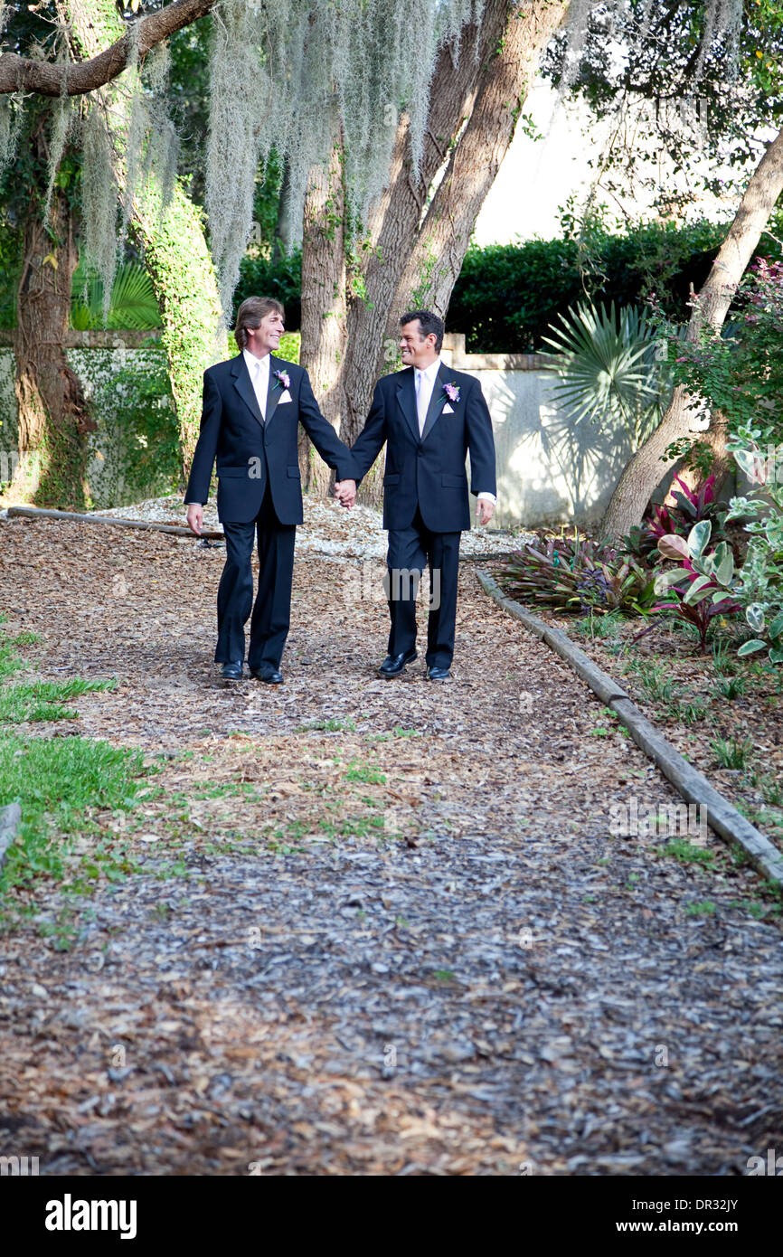 Handsome gay wedding couple walking together on the garden path, symbolizing the walk through life.  Stock Photo