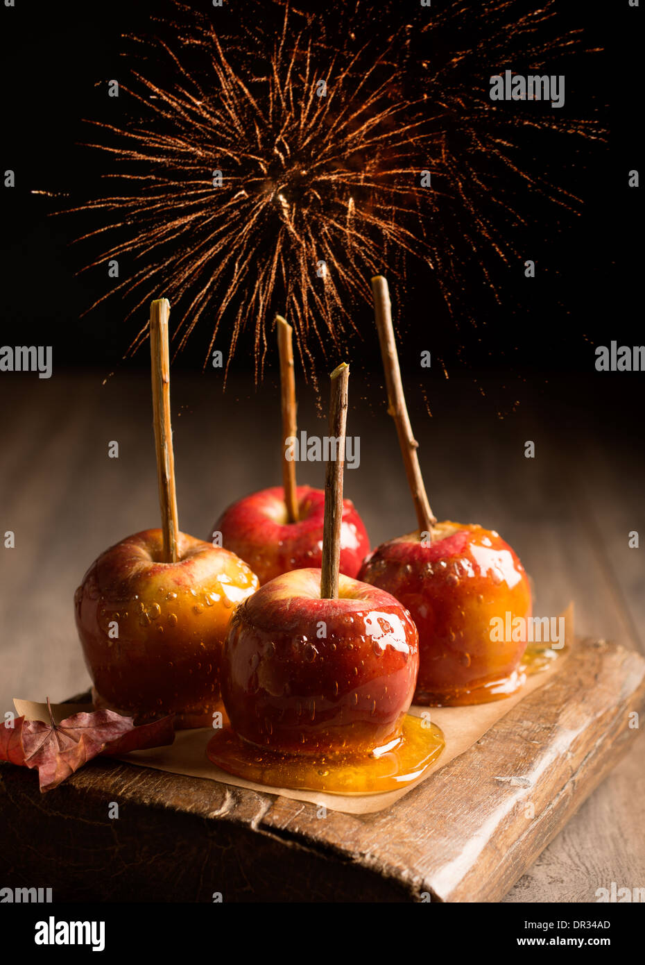 Group of toffee apples on rustic wooden board with fireworks in the background Stock Photo