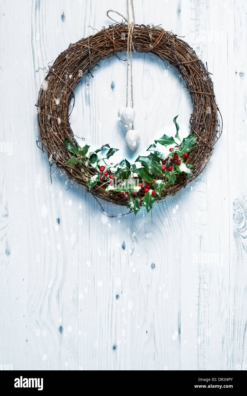 Rustic Christmas garland decorated with holly and berries hanging on white door Stock Photo