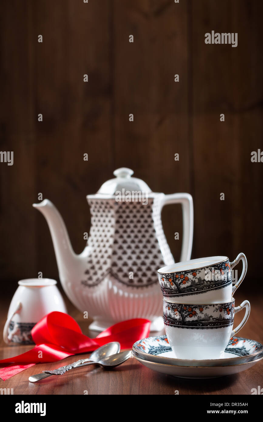 Teacups and saucers with teapot in rustic setting Stock Photo
