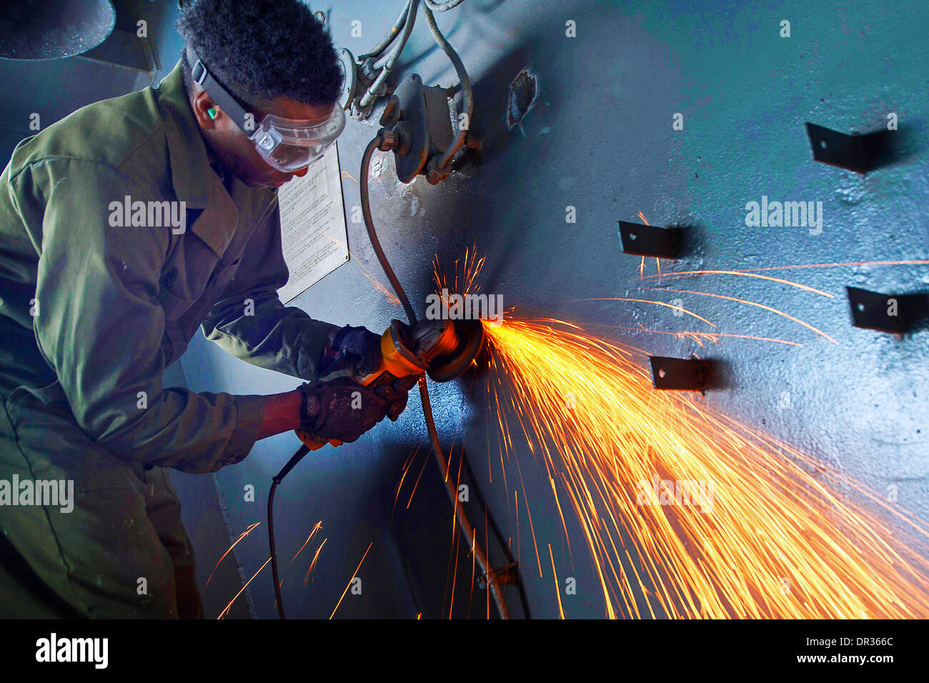 Seaman performs maintenance on a bulkhead on board the aircraft carrier USS Harry S. Truman Stock Photo