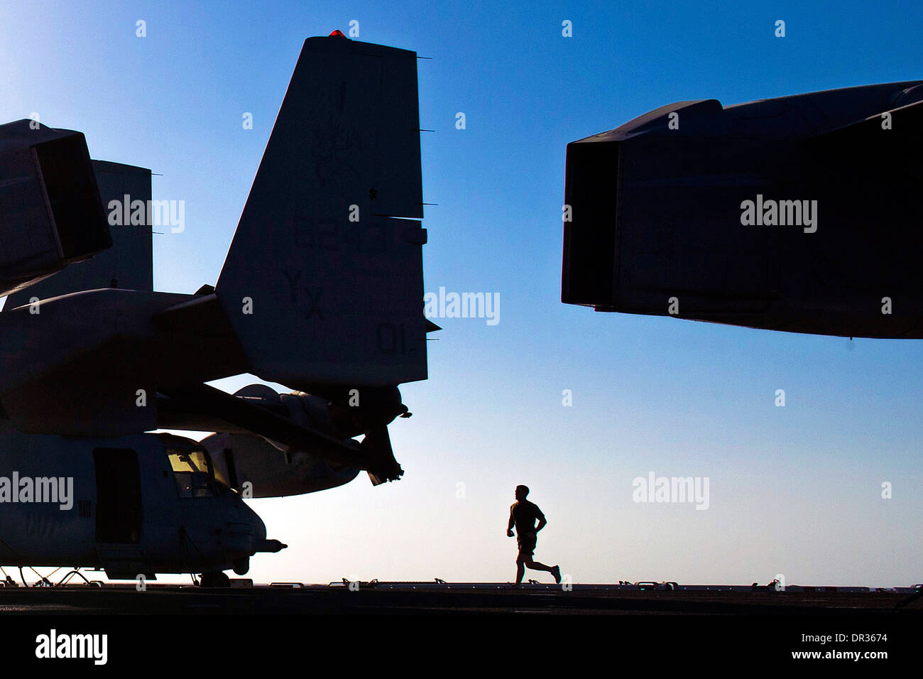 Marine runs at sunrise on the flight deck of the amphibious assault ship USS Boxer Stock Photo