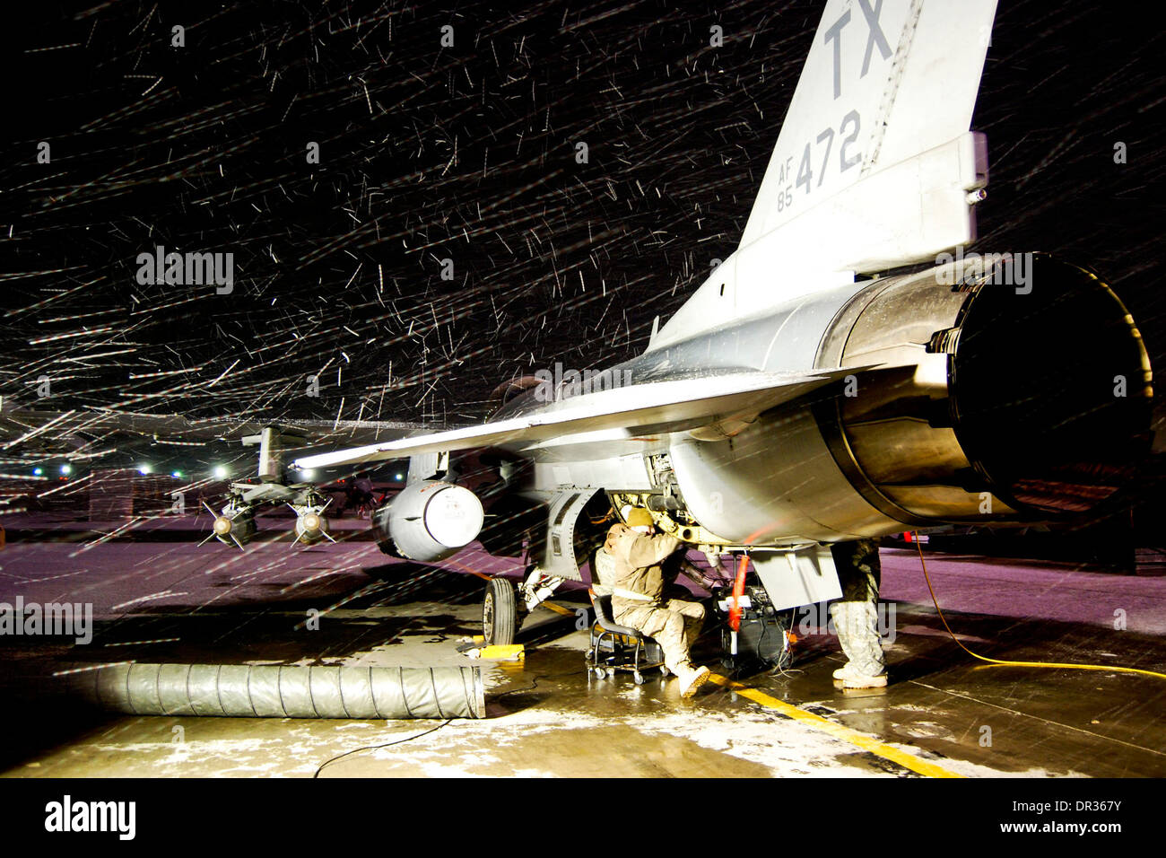 U.S. Air Force maintenance team works on an F-16 Fighting Falcon aircraft during a snowstorm at Bagram Airfield in Afghanistan Stock Photo