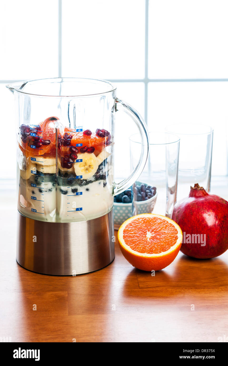 Healthy smoothie ingredients in blender with fresh fruit ready to blend