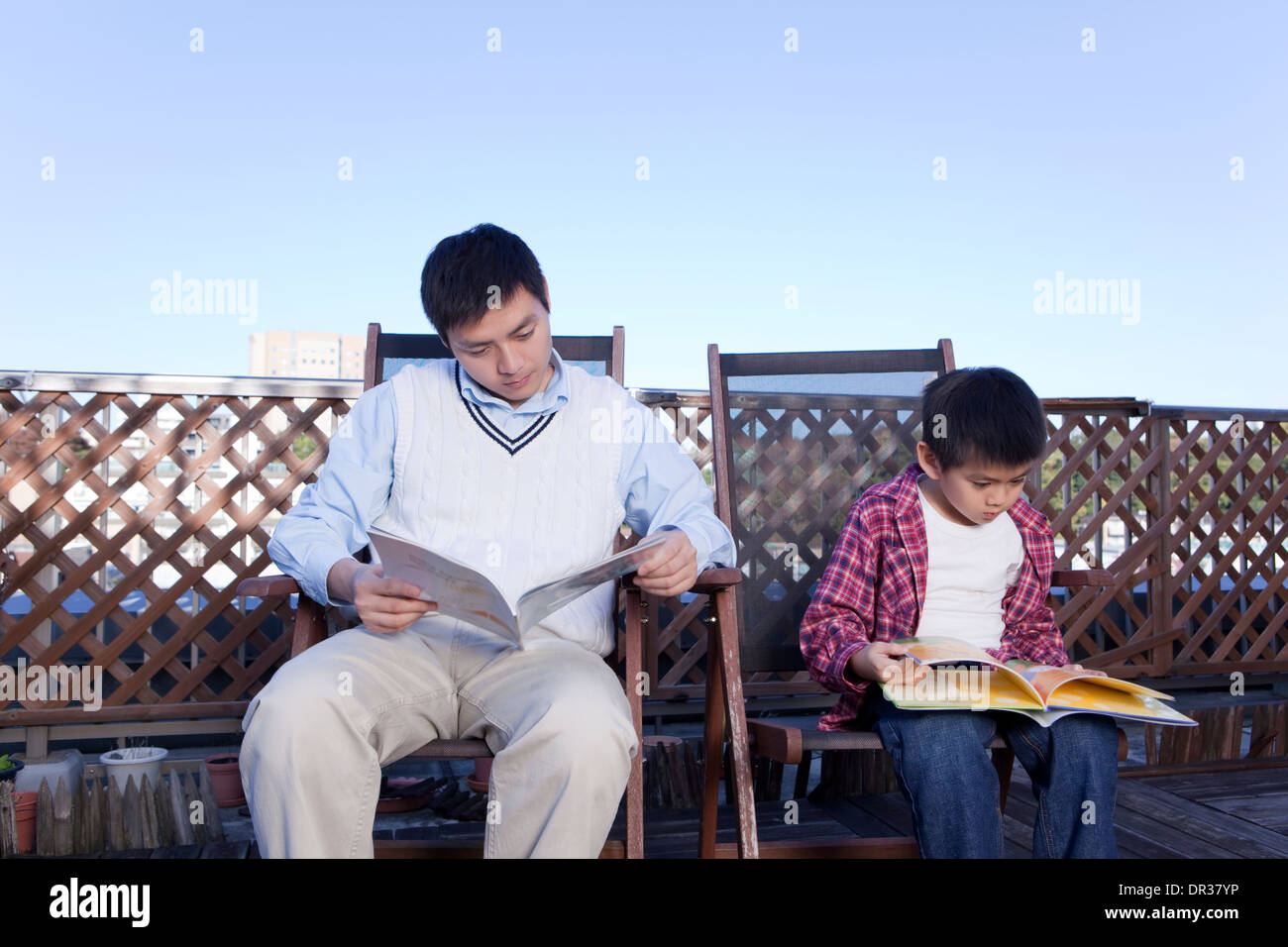 Father and son reading on balcony Stock Photo