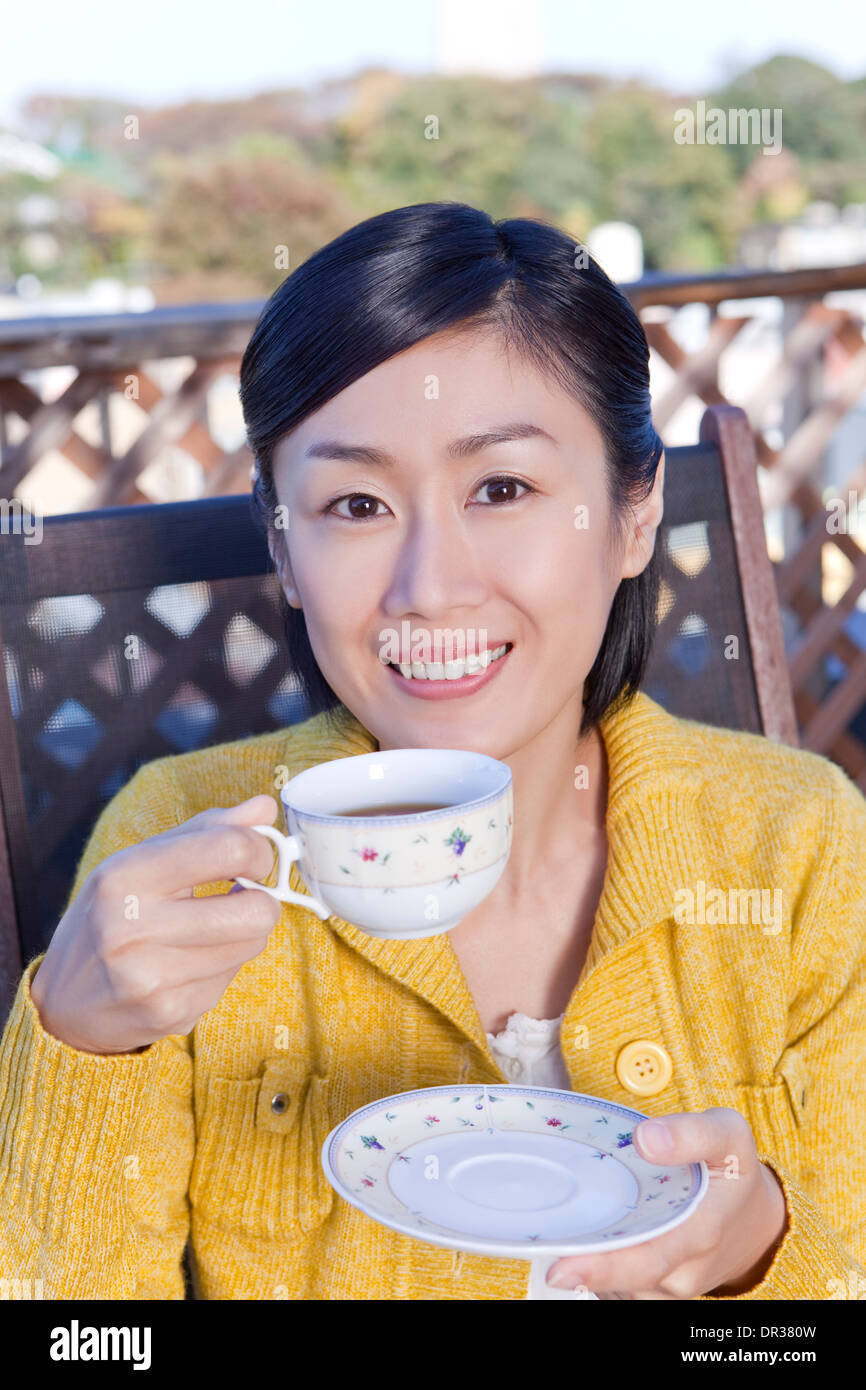 Mid adult woman having tea on balcony Stock Photo