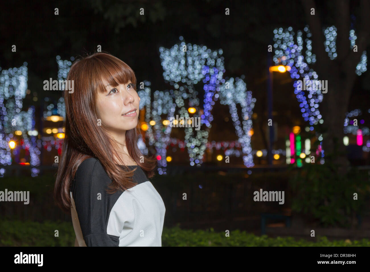Japanese female outside with volorful lights in background Stock Photo