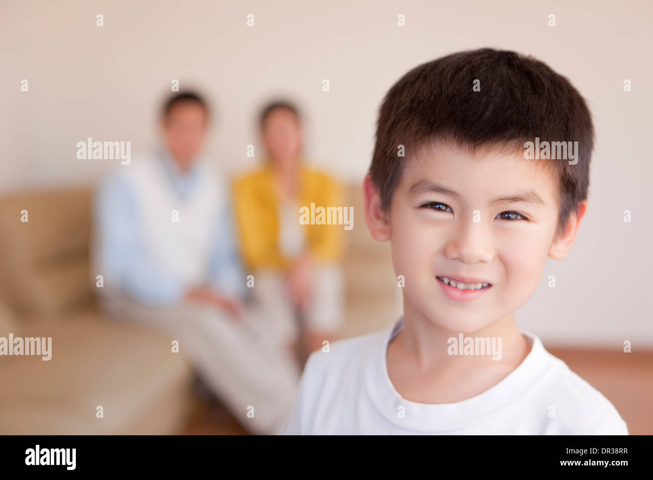 Boy looking at camera, parents in background Stock Photo