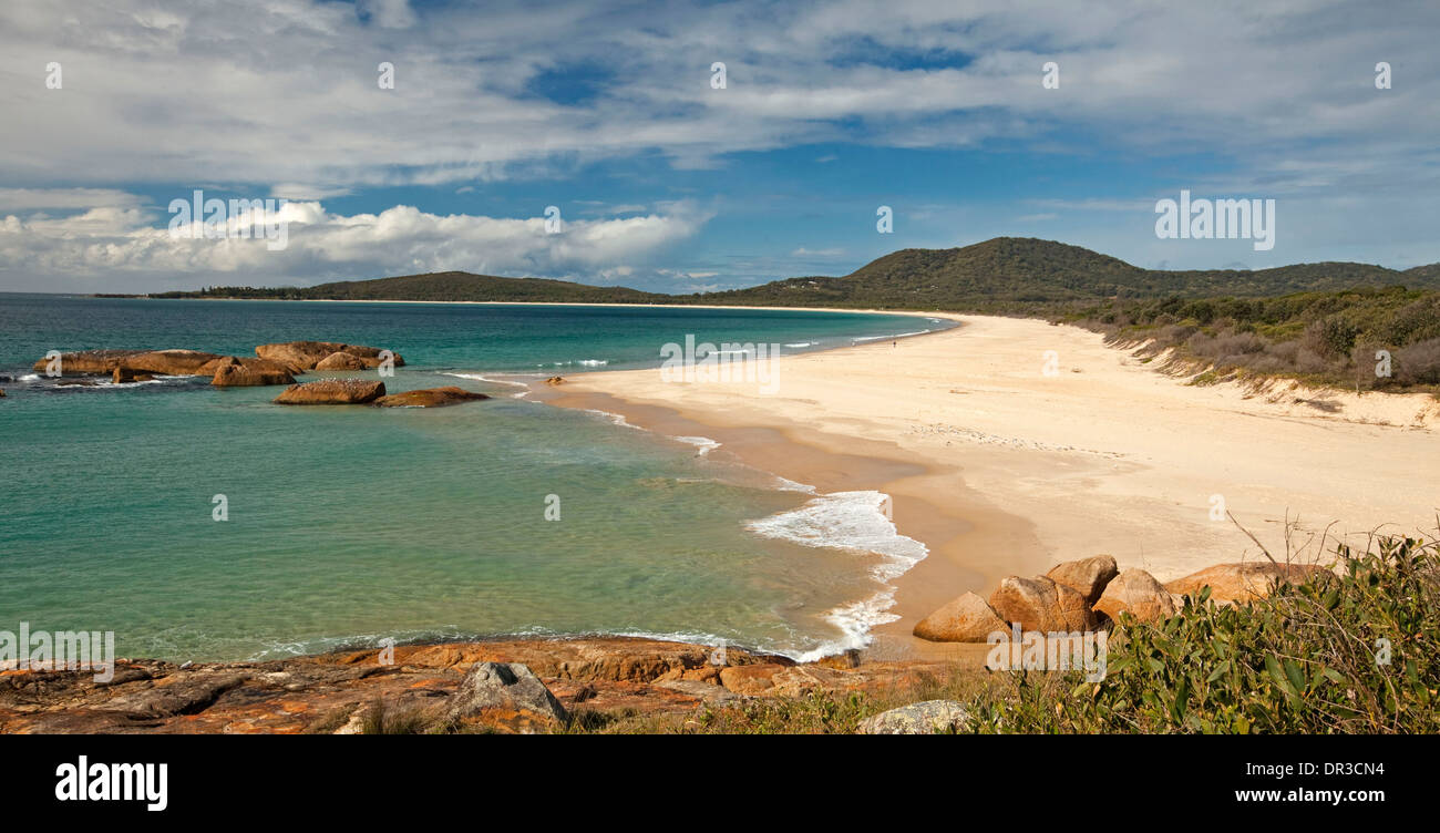Turquoise Pacific Ocean and vast deserted sandy beach in large picturesque bay hemmed by forested hills at South West Rocks NSW Stock Photo