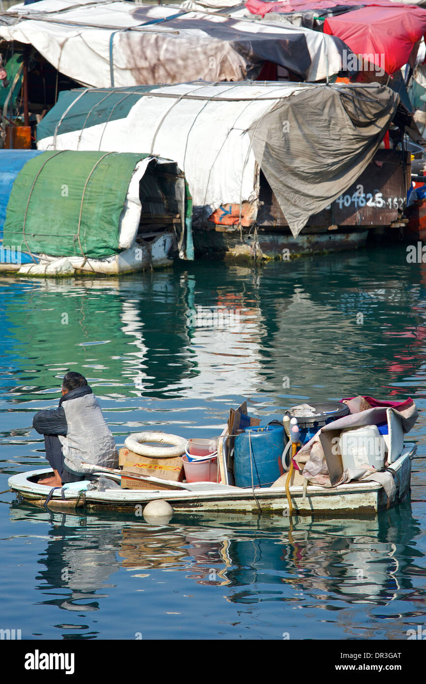 Old Chinese man sits on the bow of an overloaded dinghy in the Causeway