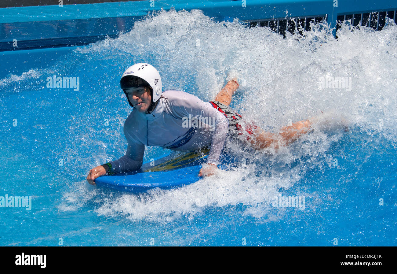 Board rider body surfing on water of wave machine at water park in