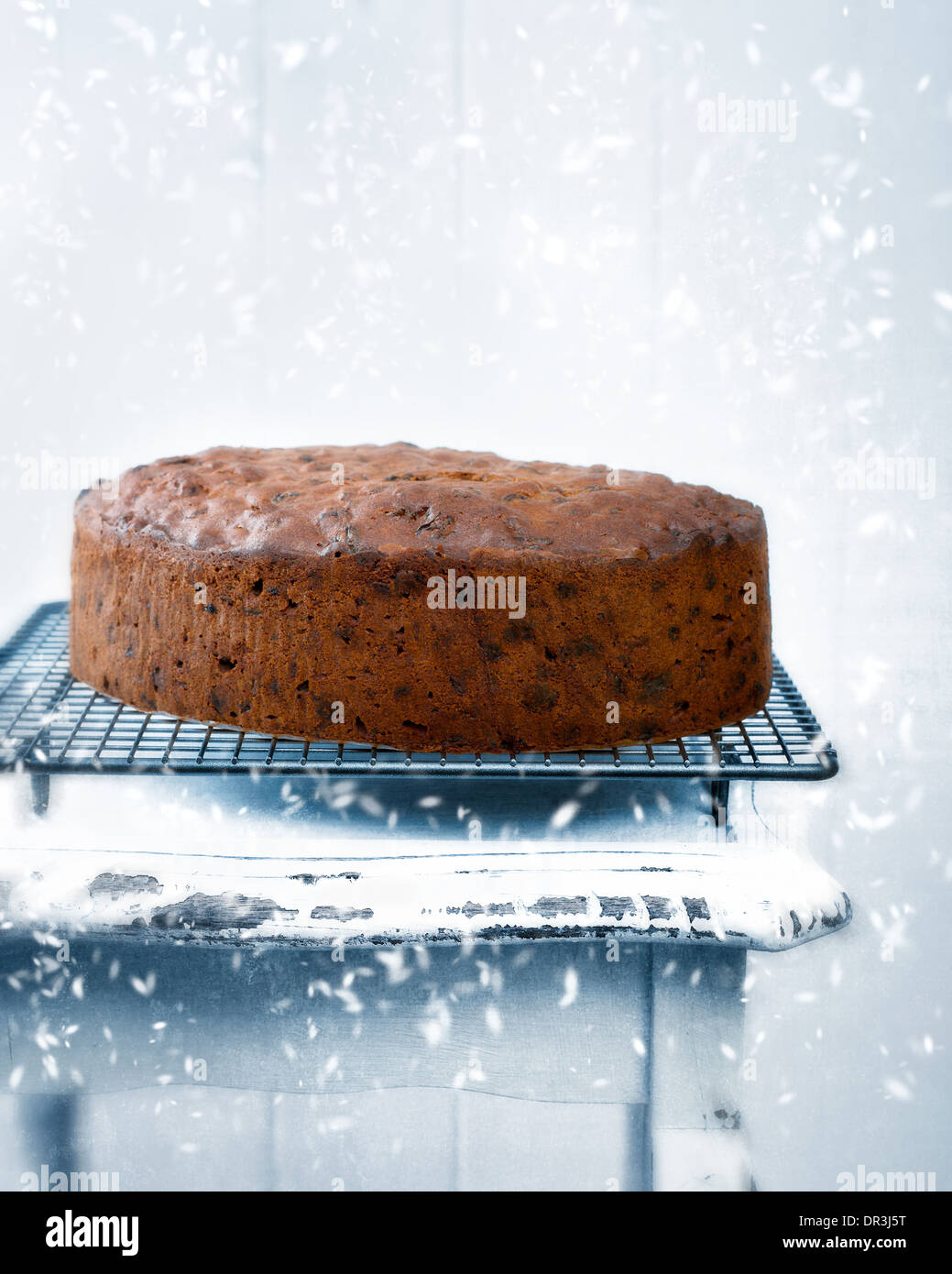 Christmas fruit cake freshly baked with falling snow and winter toned effect Stock Photo