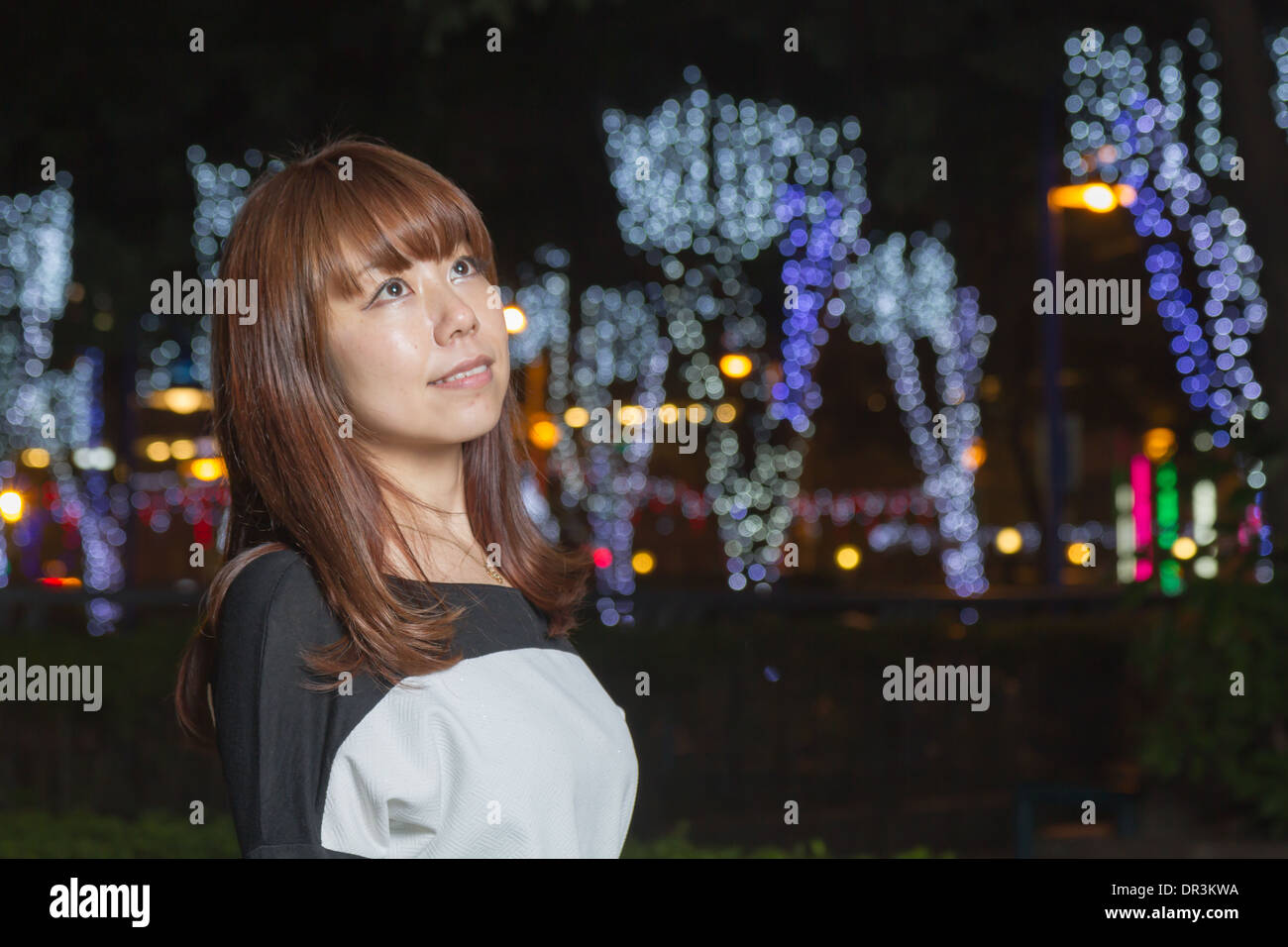 Japanese female outside with volorful lights in background Stock Photo