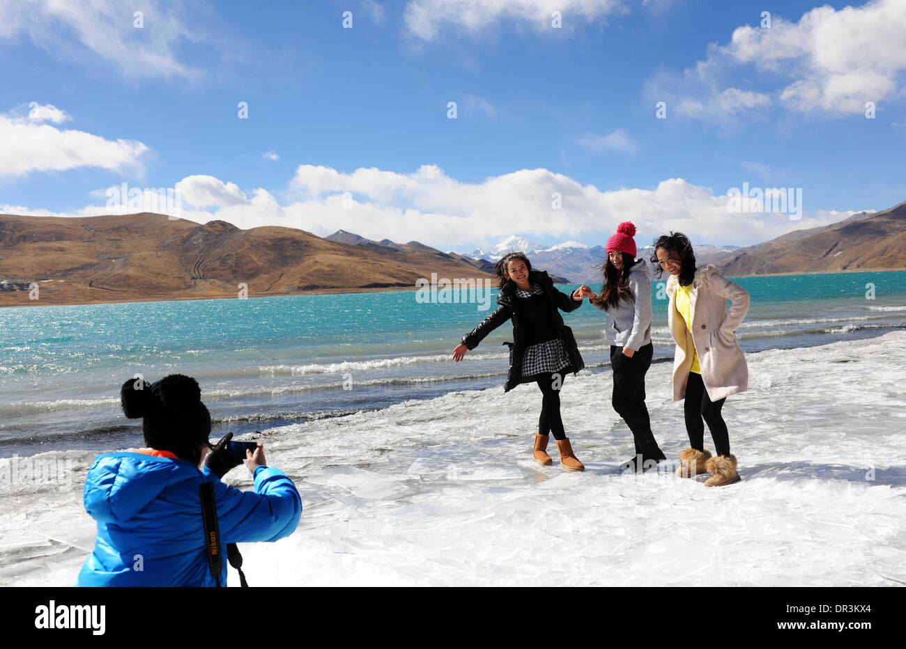 Shannan, China's Tibet Autonomous Region. 19th Jan, 2014. Tourists pose for photos by the side of Yamzho Yumco Lake in Shannan Prefecture, southwest China's Tibet Autonomous Region, Jan. 19, 2014. Yamzho Yumco Lake, considered as one of the three sacred lakes in Tibet, is a good choice of travel destination in winter. © Wen Tao/Xinhua/Alamy Live News Stock Photo