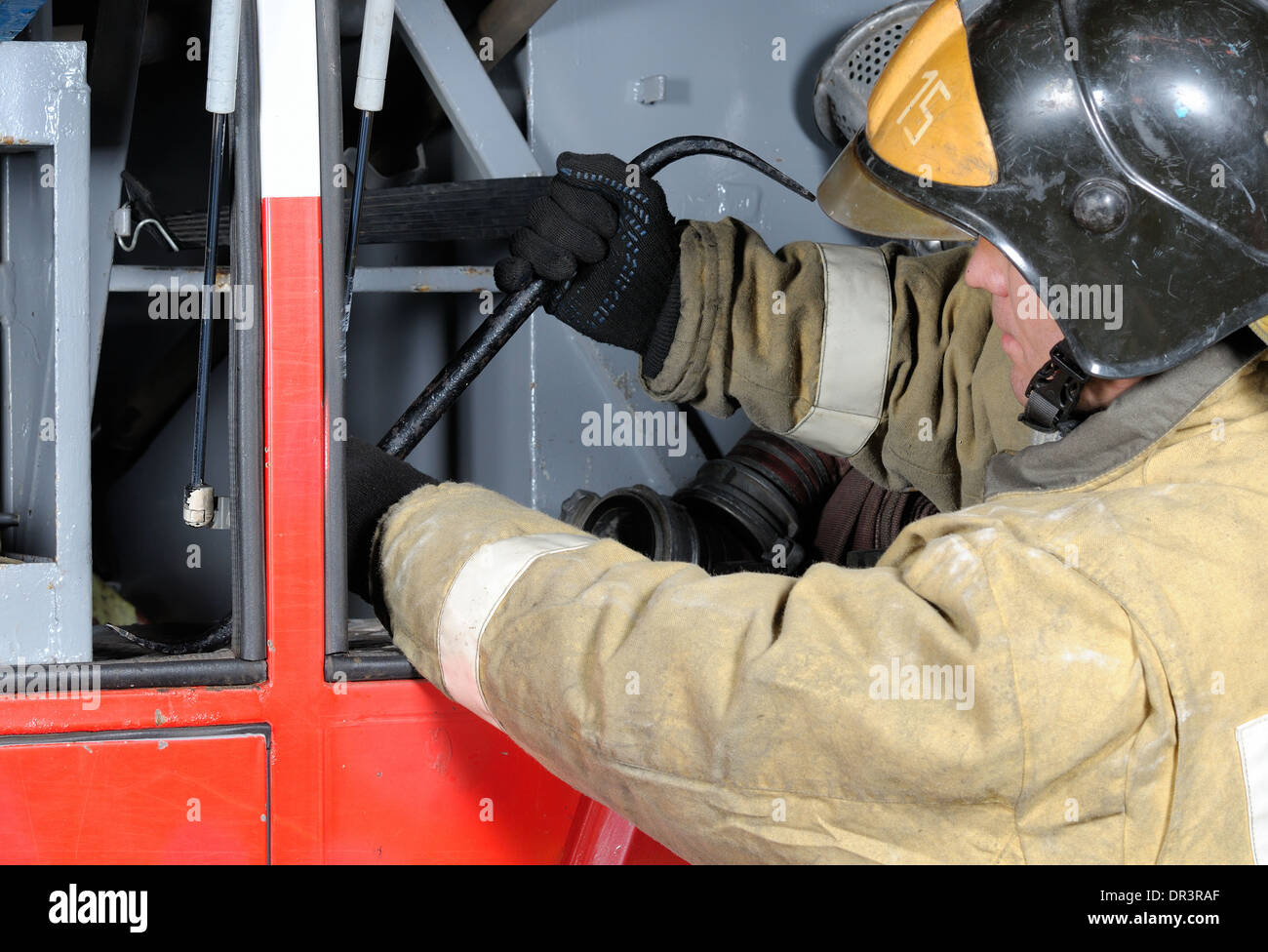 Firefighter pulls the crowbar from the compartment of fire engine Stock Photo