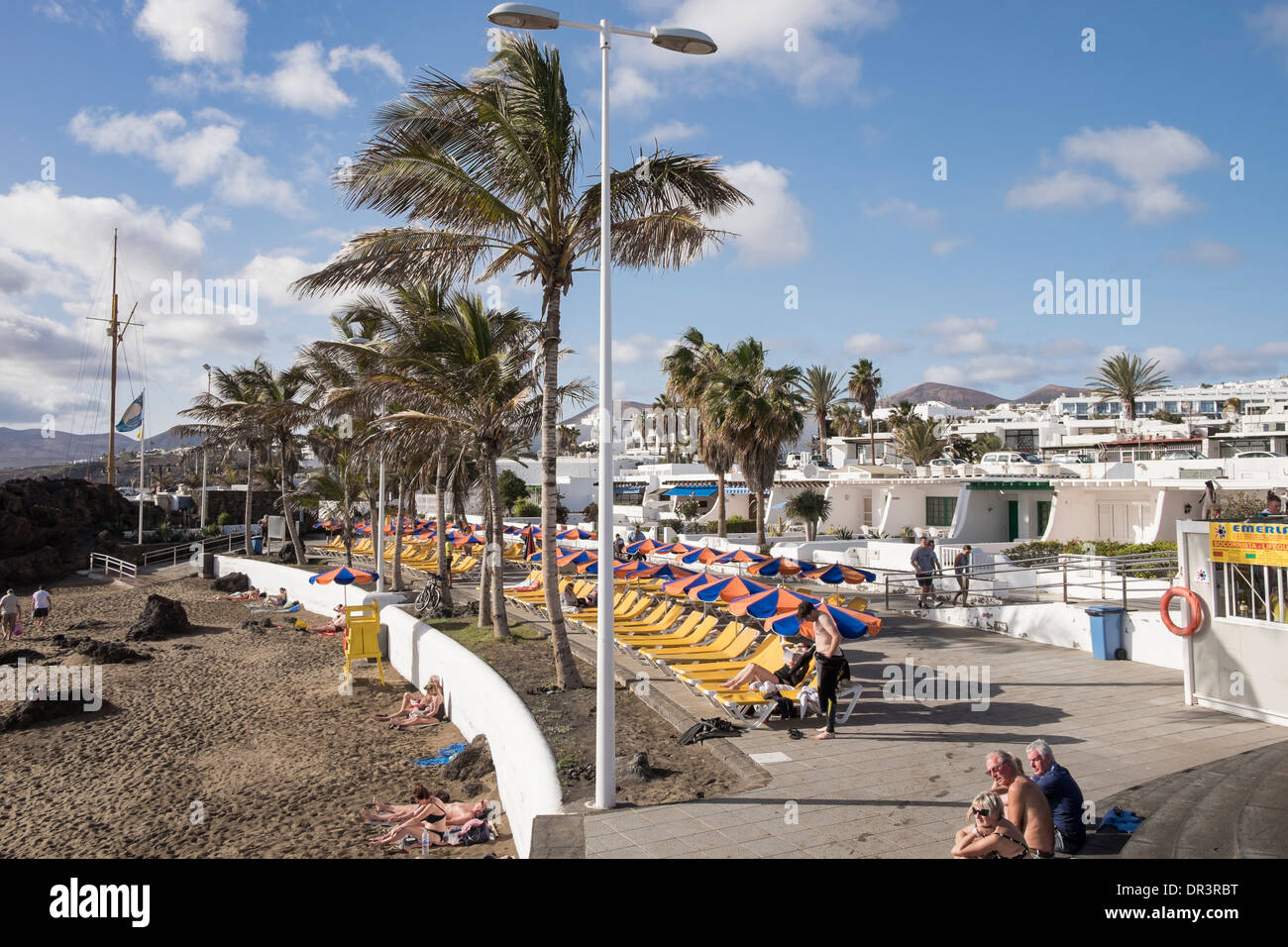 Typical white holiday apartments on waterfront lined with sunbeds