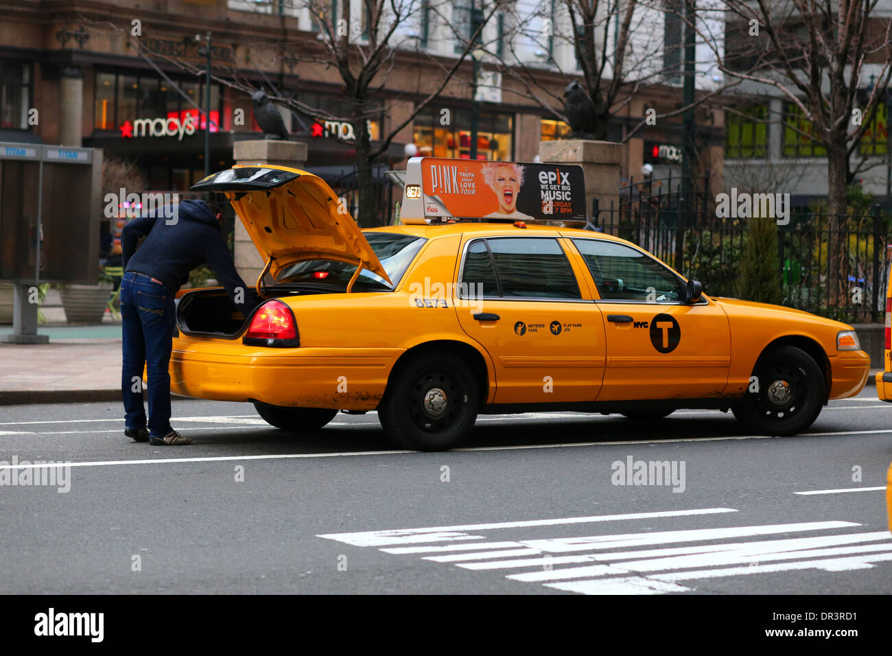 A person checks the truck of a taxi cab in New York City Stock Photo
