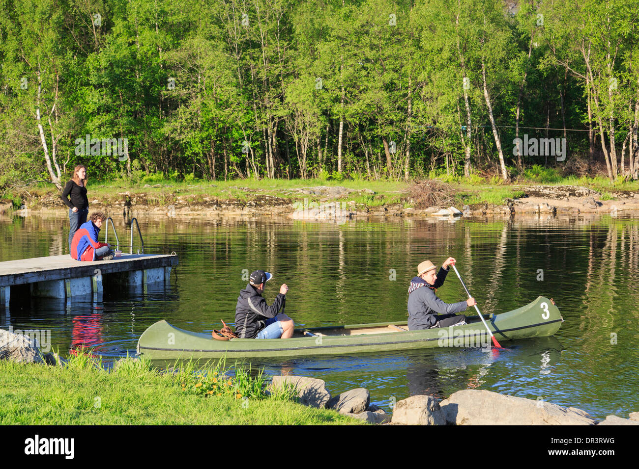 Two men paddling a Canadian canoe on Lake Haukeland in summer near
