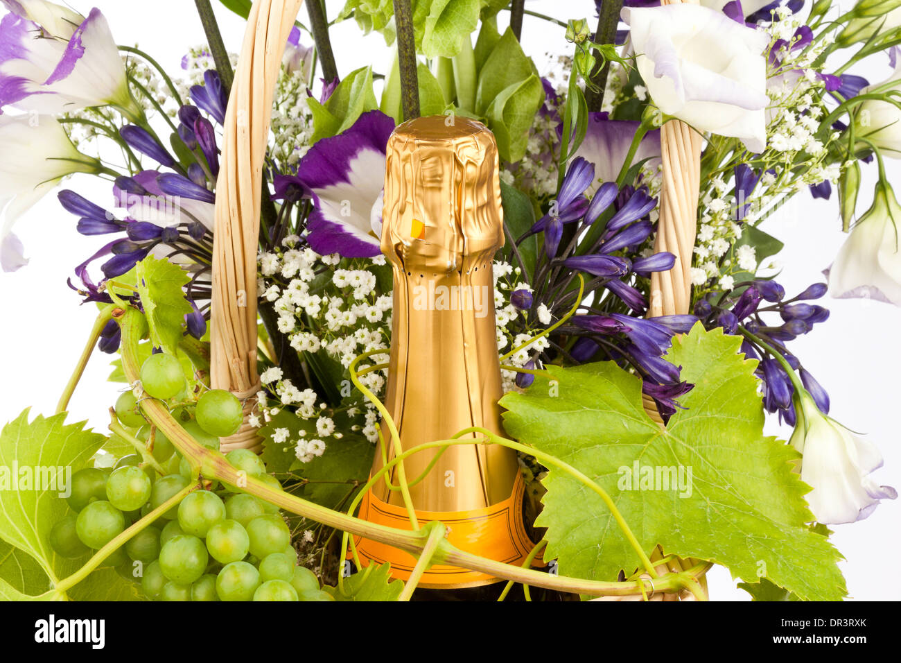 A wine basket containing a bottle of champagne and a flower and grape arrangement Stock Photo