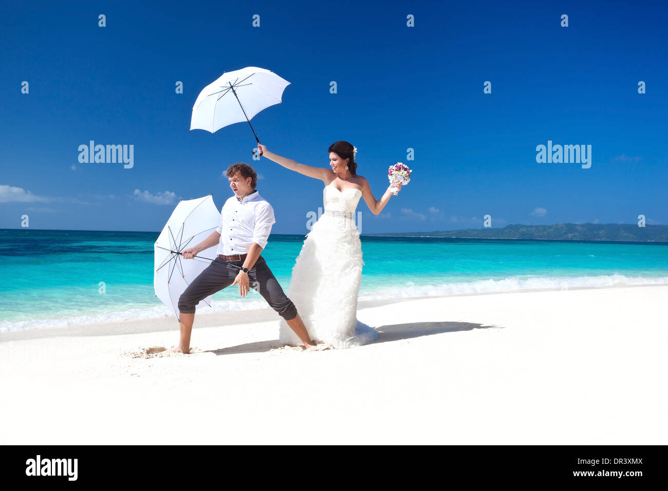 Bride And Groom On The Beach Having Fun With Umbrellas Tropical
