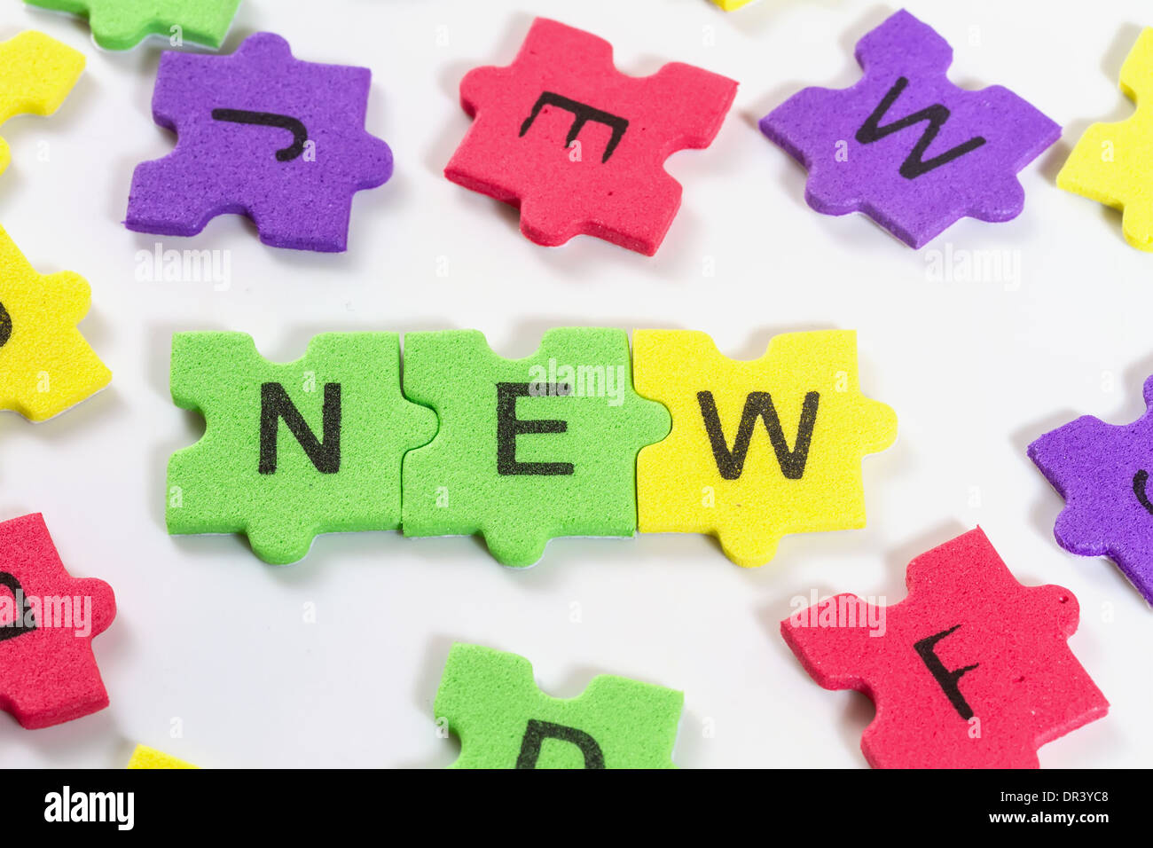 word NEW formed with colorful foam puzzle on white background Stock