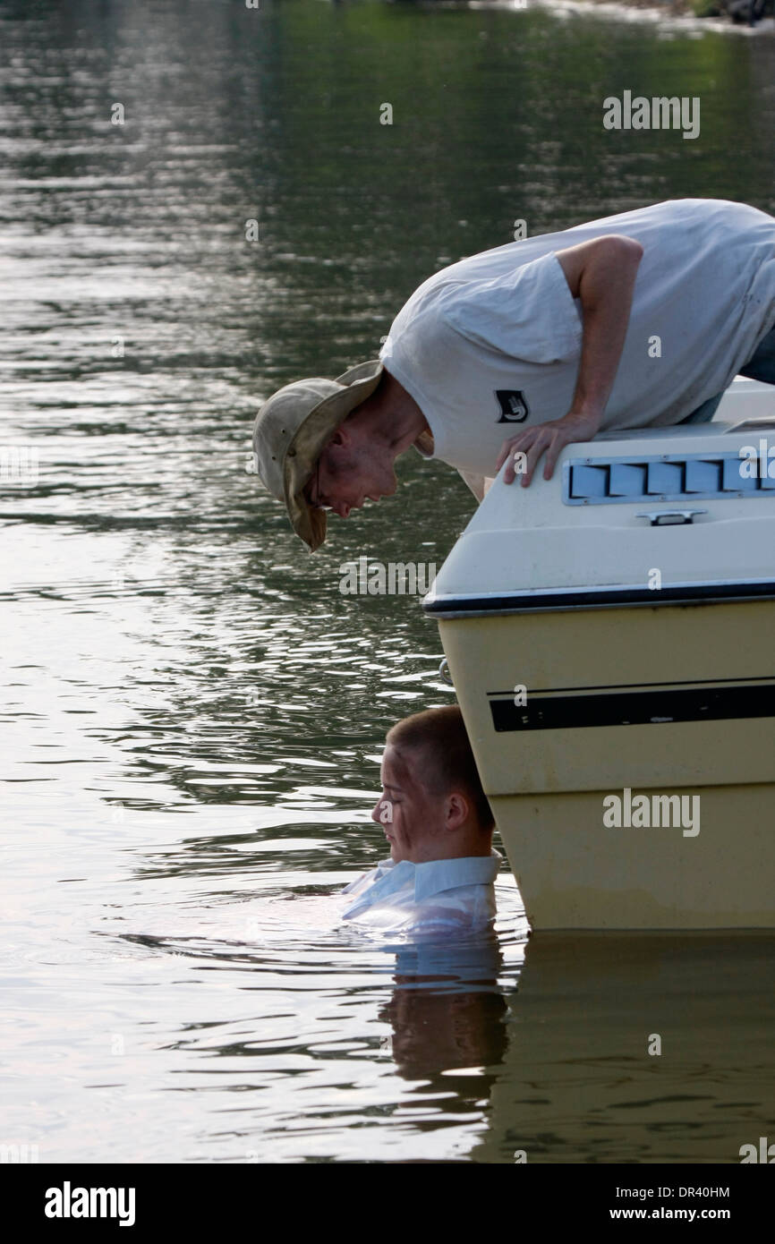 Boating accident victim in the water being checked on by another person Stock Photo