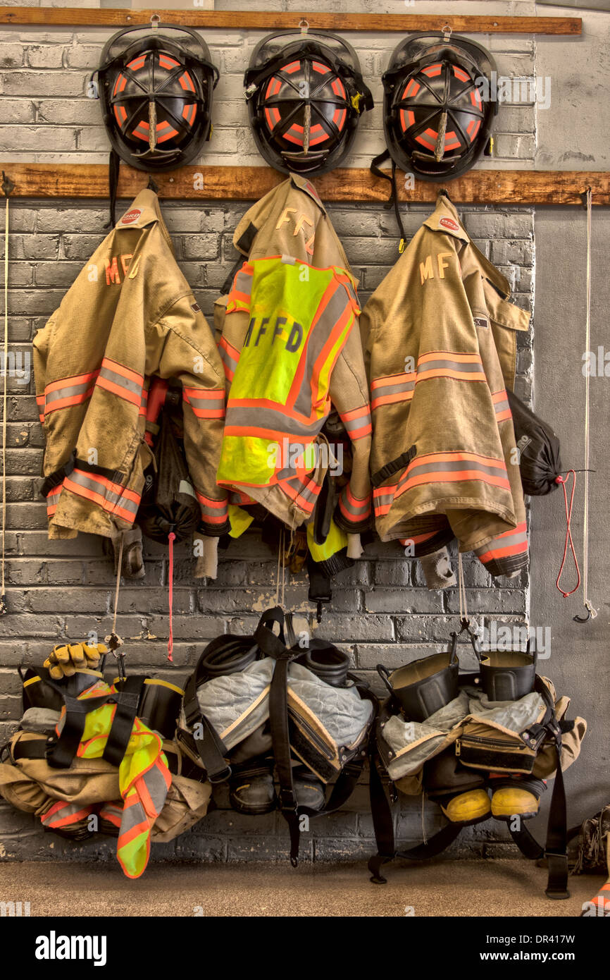 Three firefighter uniforms hanging on the station wall HDR Stock Photo
