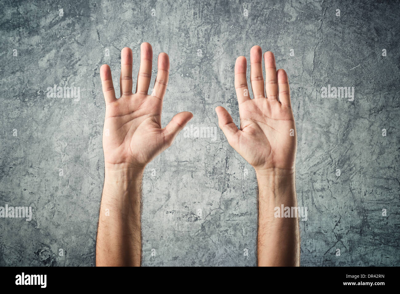Caucasian male open hands raised as surrender gesture on grunge background Stock Photo