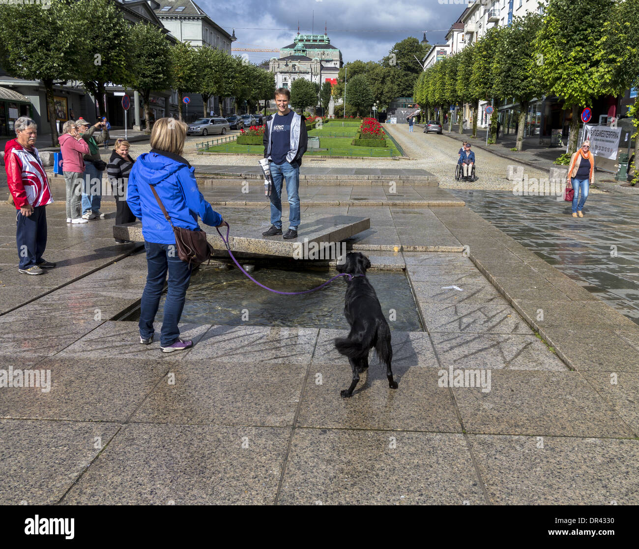 Woman with dog watching man standing on a concrete pedestal Ole Bulls Plass Bergen Norway Stock Photo