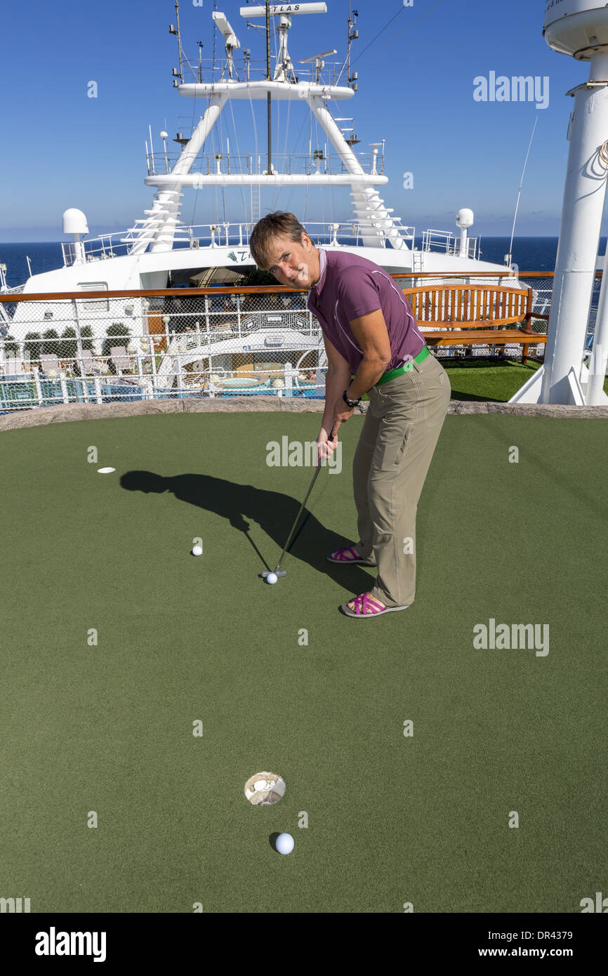 Woman on the synthetic putting green on board a cruise ship Stock Photo