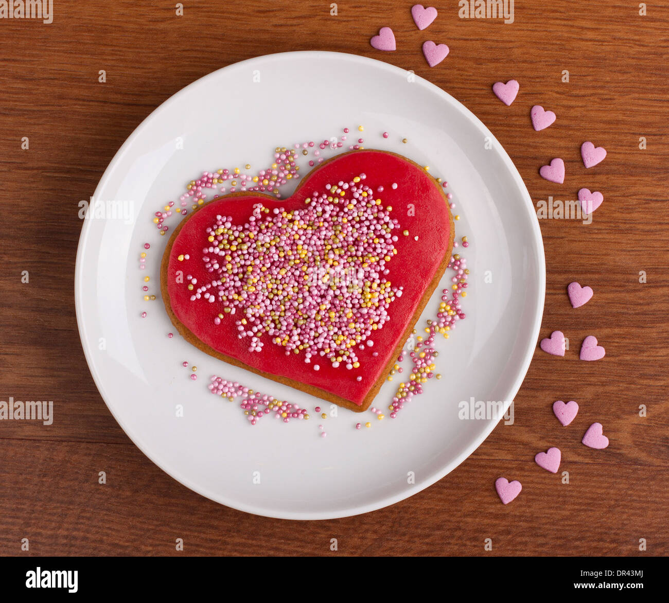 Red marzipan biscuit covered with pink sugar sprinkles Stock Photo