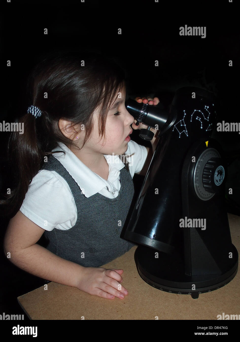 Young girl in school uniform with an astronomical telescope Stock Photo