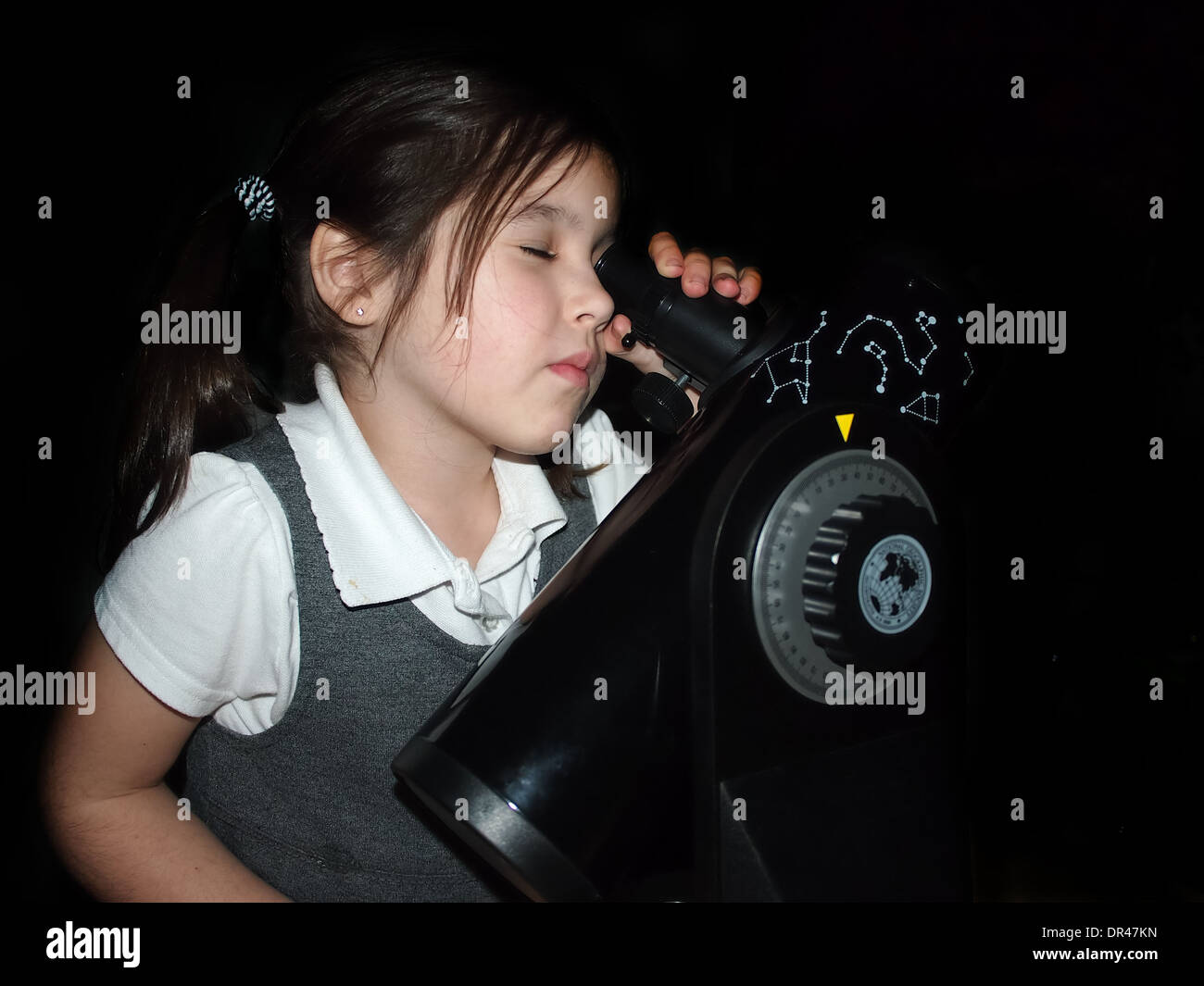 Young girl in school uniform with an astronomical telescope Stock Photo