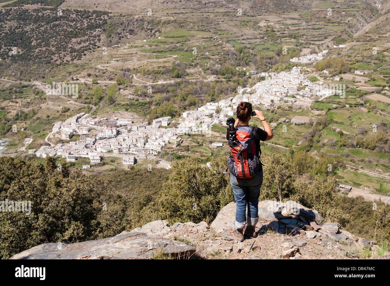 Female walker om mountain footpath overlooking Trevelez village in La