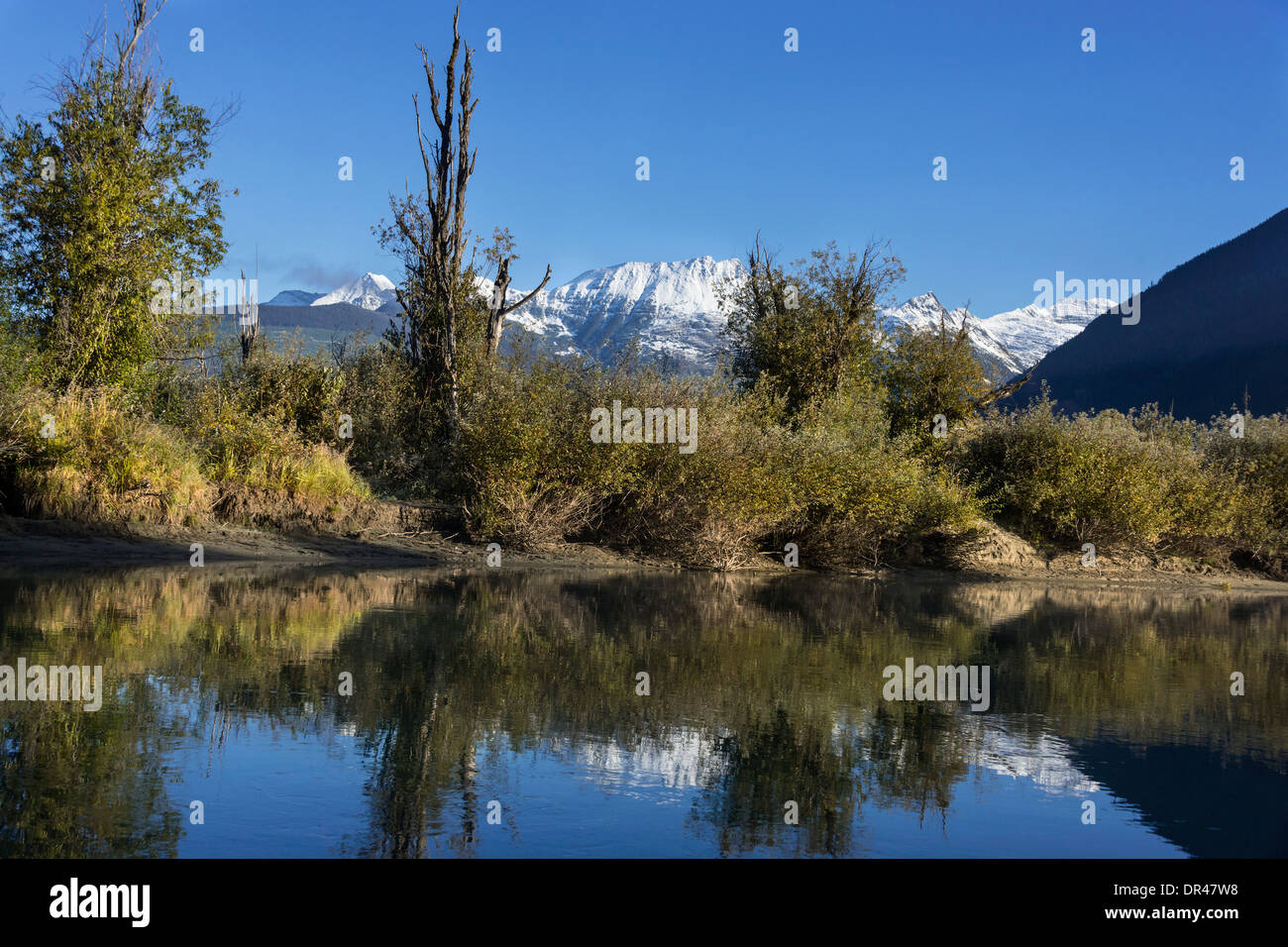 Fall colors and snowy mountains reflecting in the Mitchell River, Cariboo-Chilcotin region, British Columbia Stock Photo