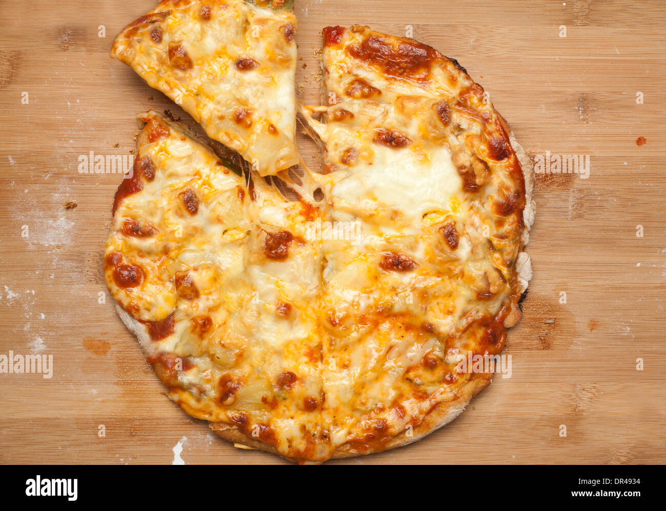 Whole cheese pizza with first slice being taken Stock Photo
