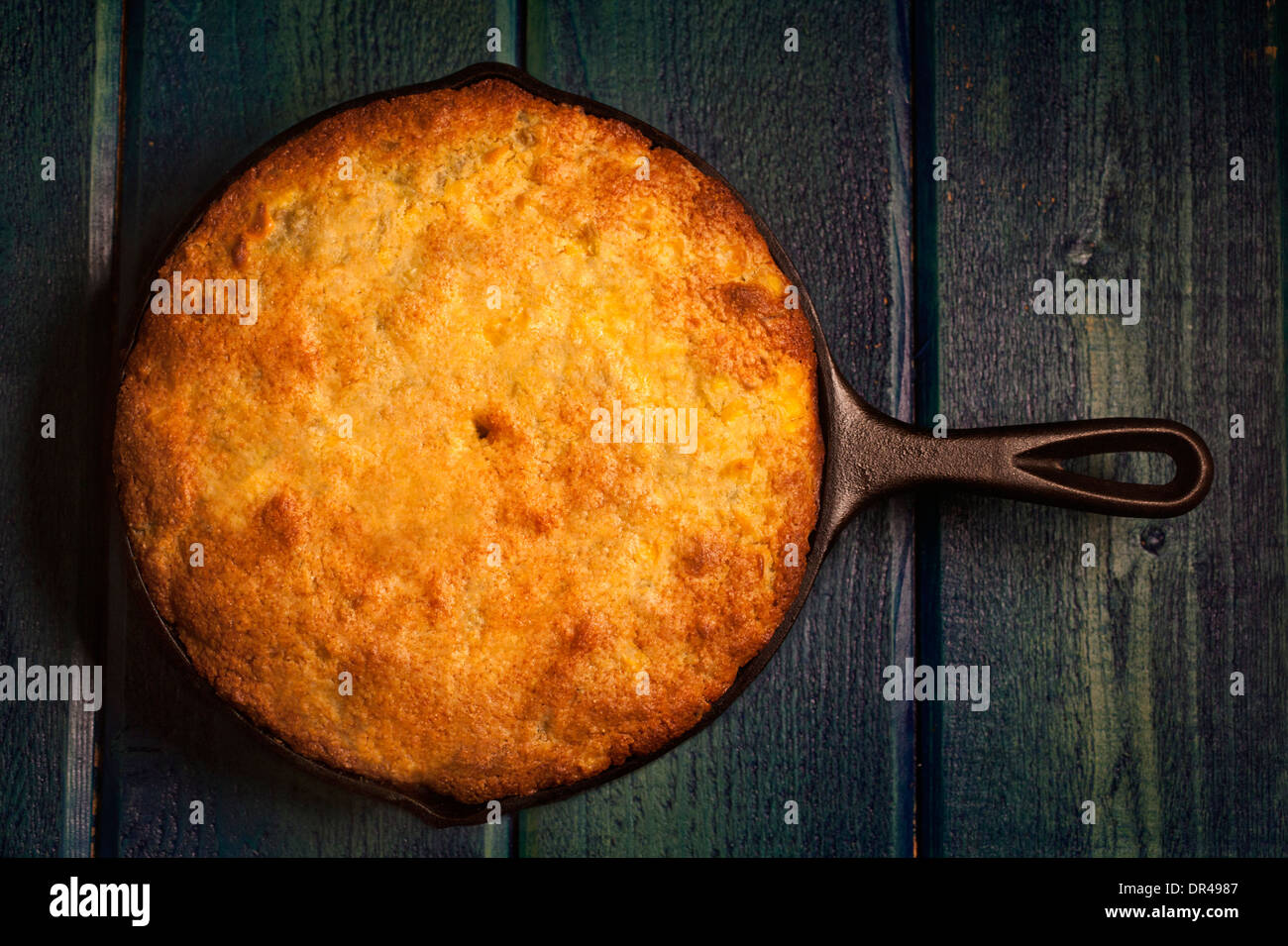 Whole round cornbread cooked in a cast iron skillet overhead Stock