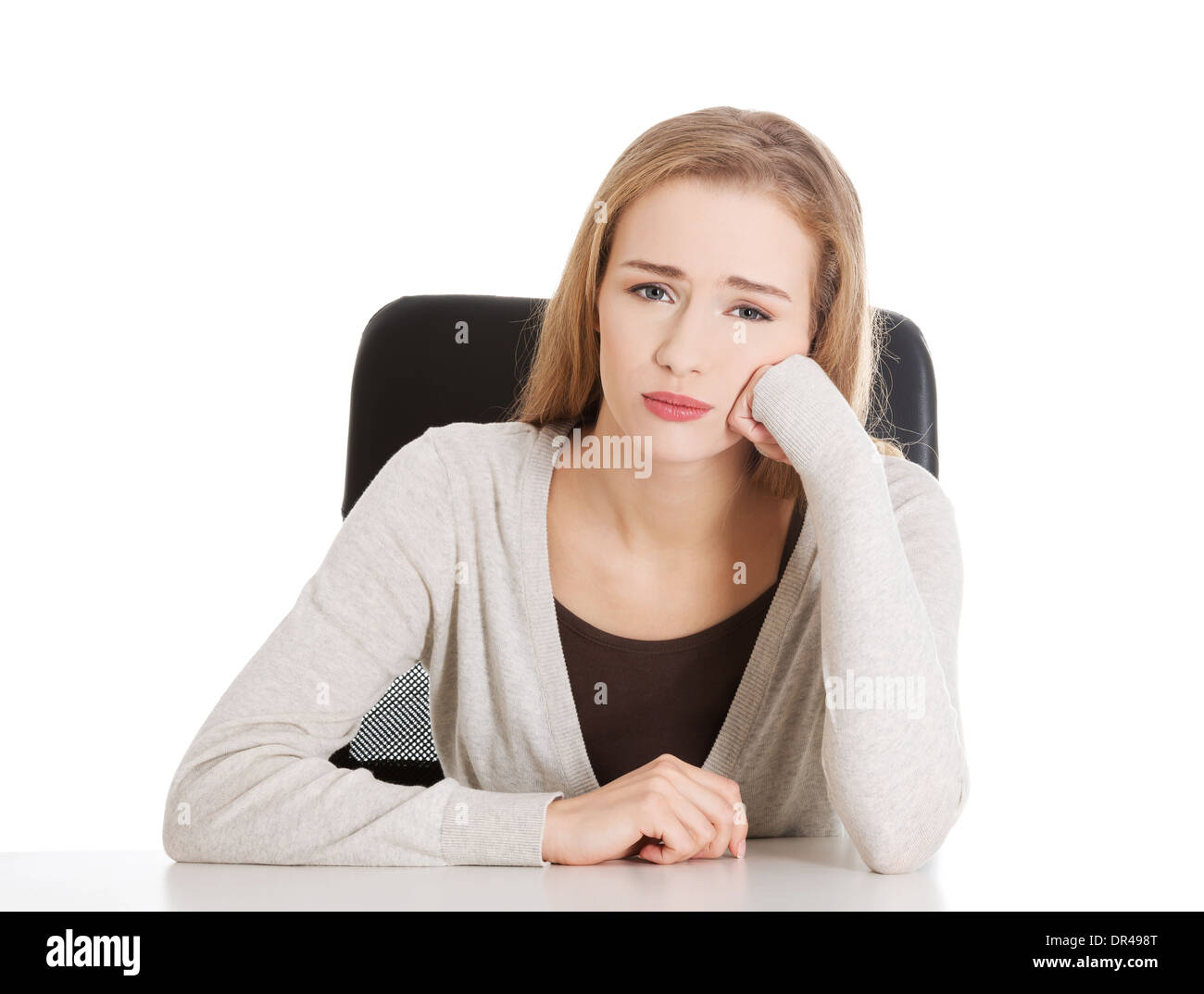 Sad, worried beautiful woman sitting by a desk. Isolated on white Stock ...