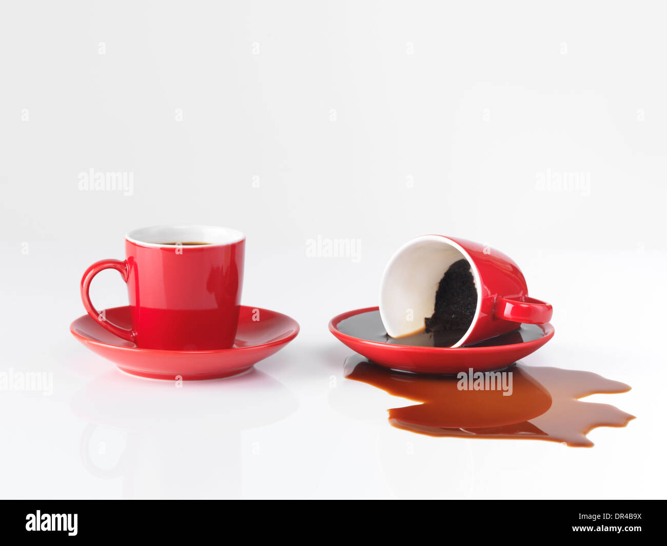 two red espresso coffee cups one cup with spilled coffee isolated