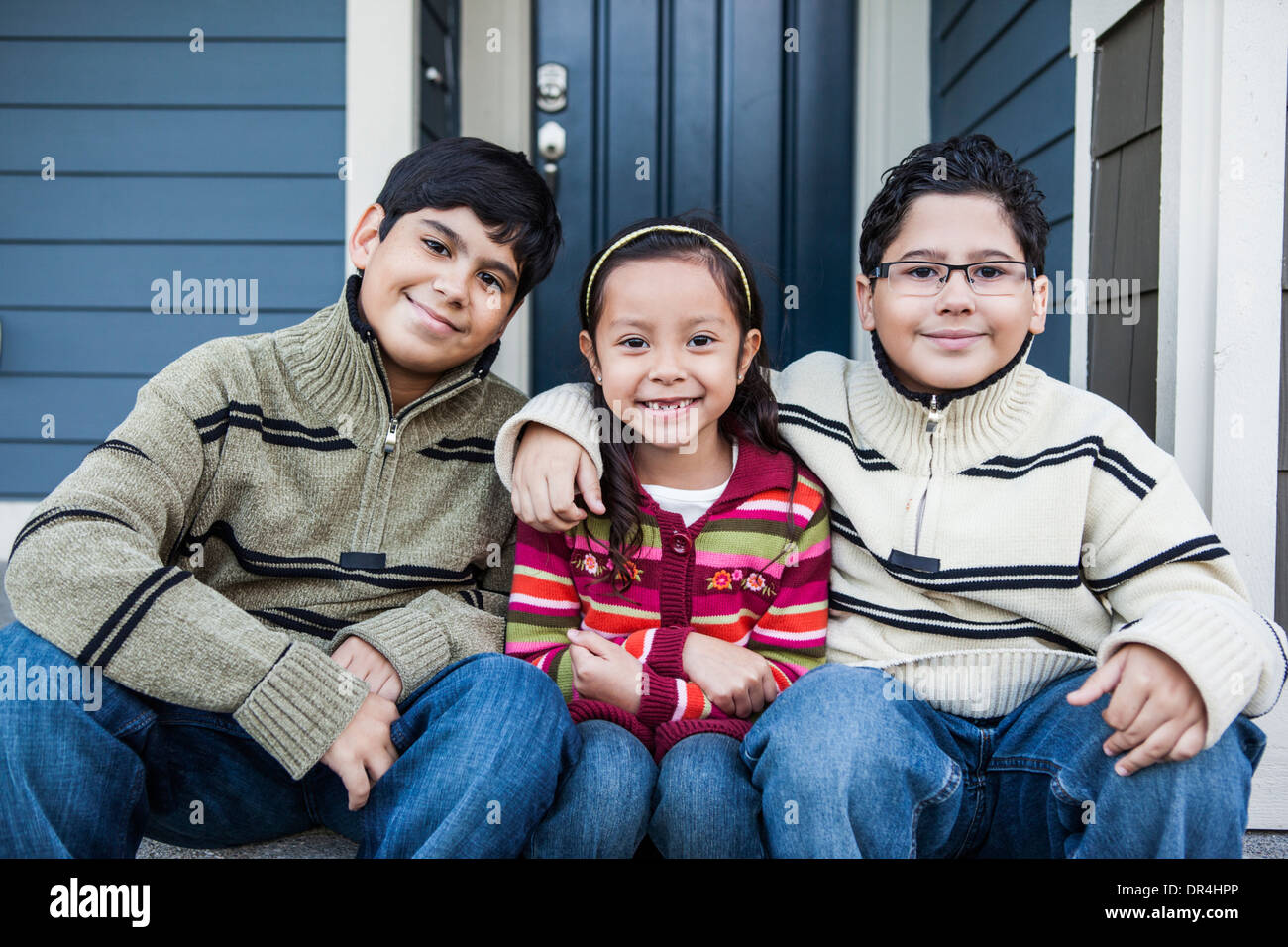 Children smiling together on front stoop Stock Photo