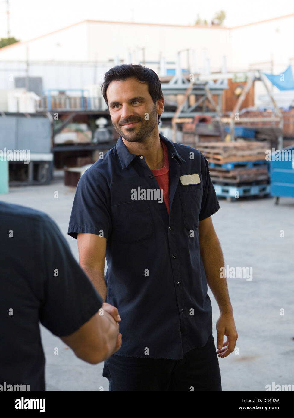 Workers shaking hands in warehouse Stock Photo